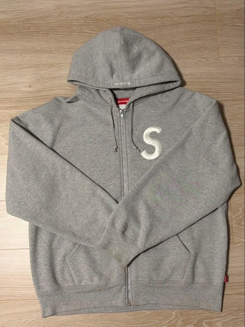 Sの刺繍が特徴のグレーのフルジップパーカー。